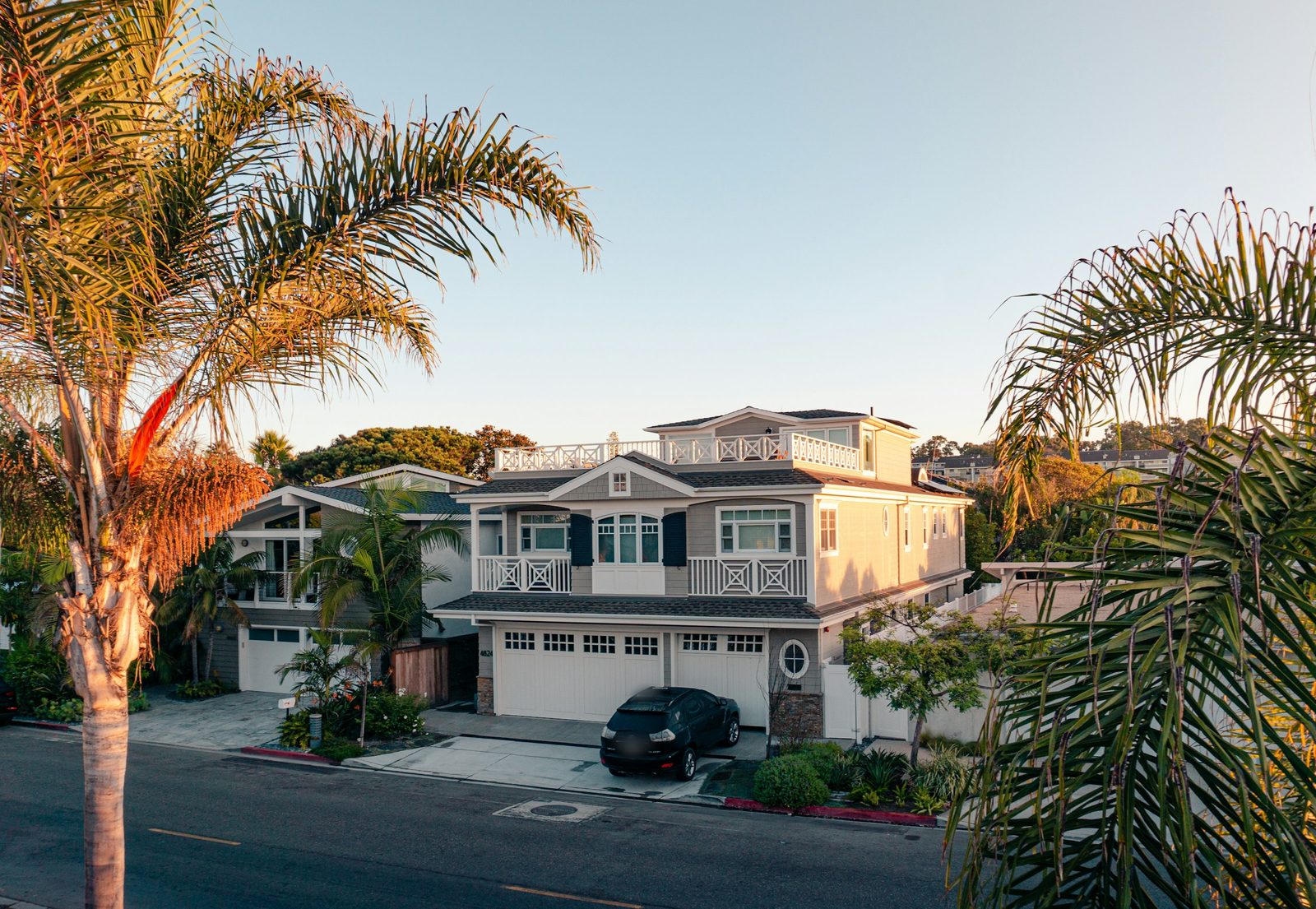 A two-storey house with palm trees in warm evening light