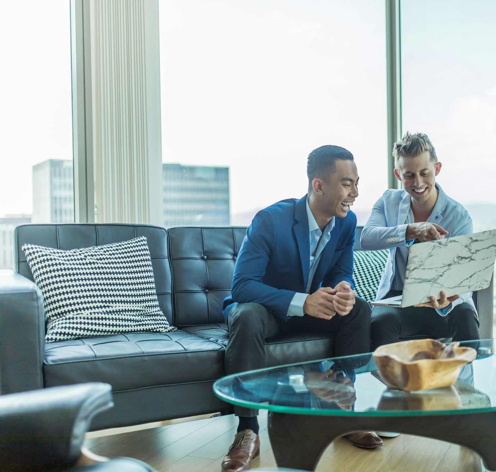 Two business partners on a sofa looking at a laptop together