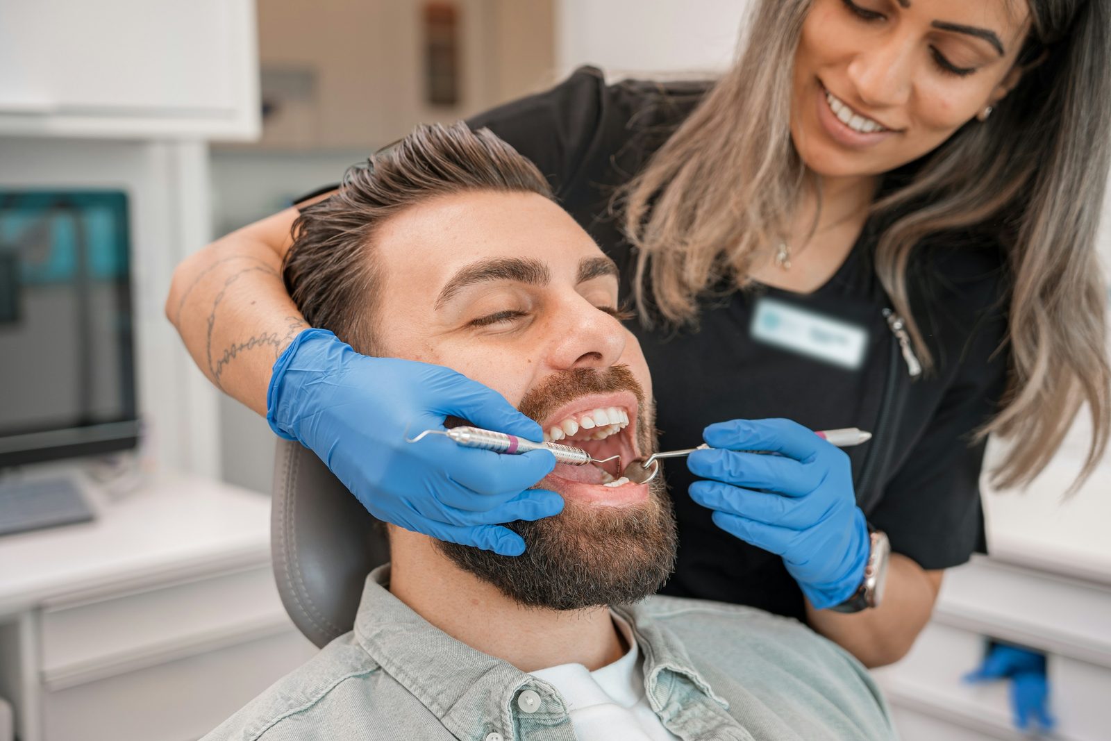 A dental hygienist examining a smiling patient