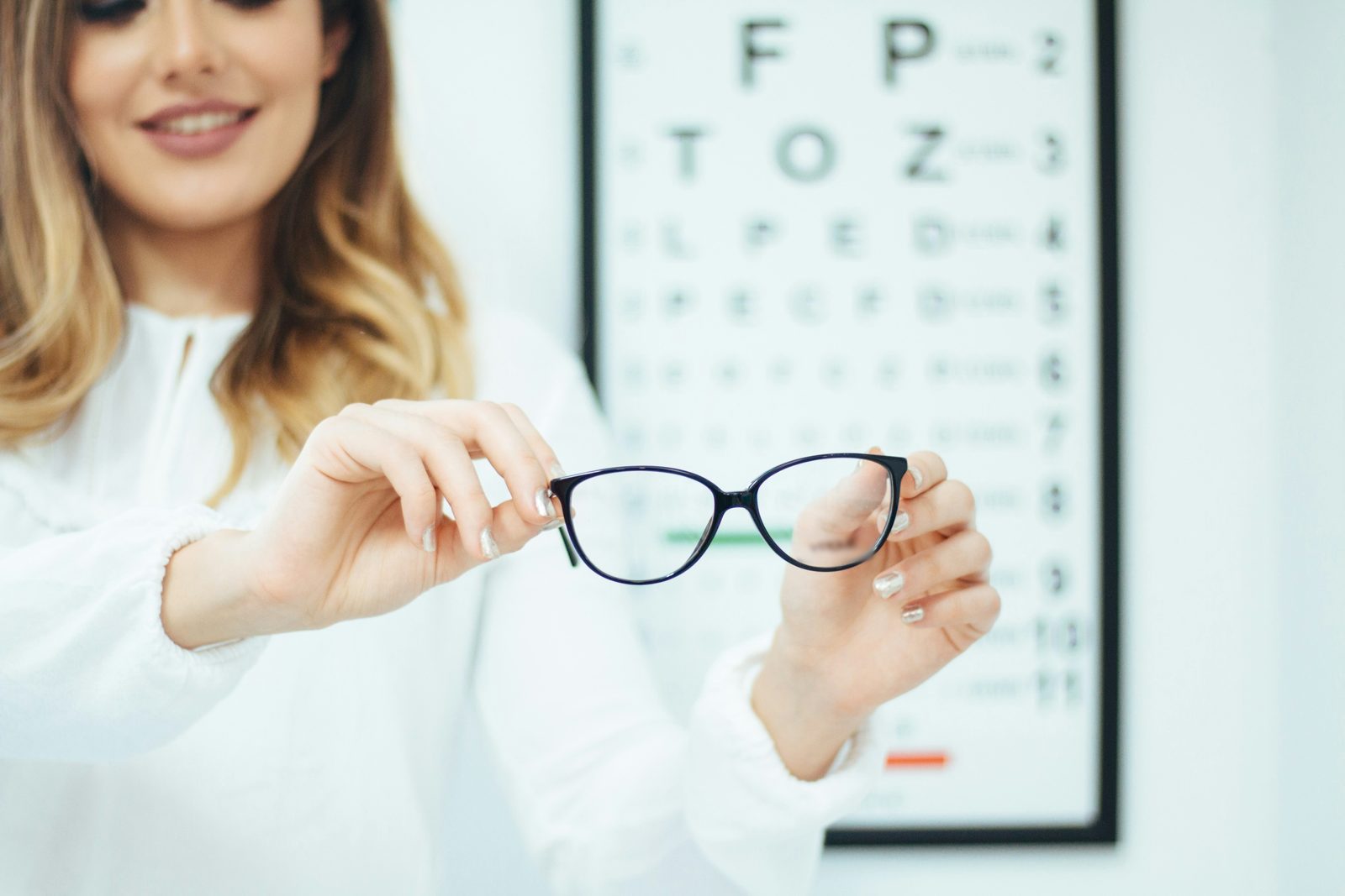 Eyeglasses held up in front of an eye chart