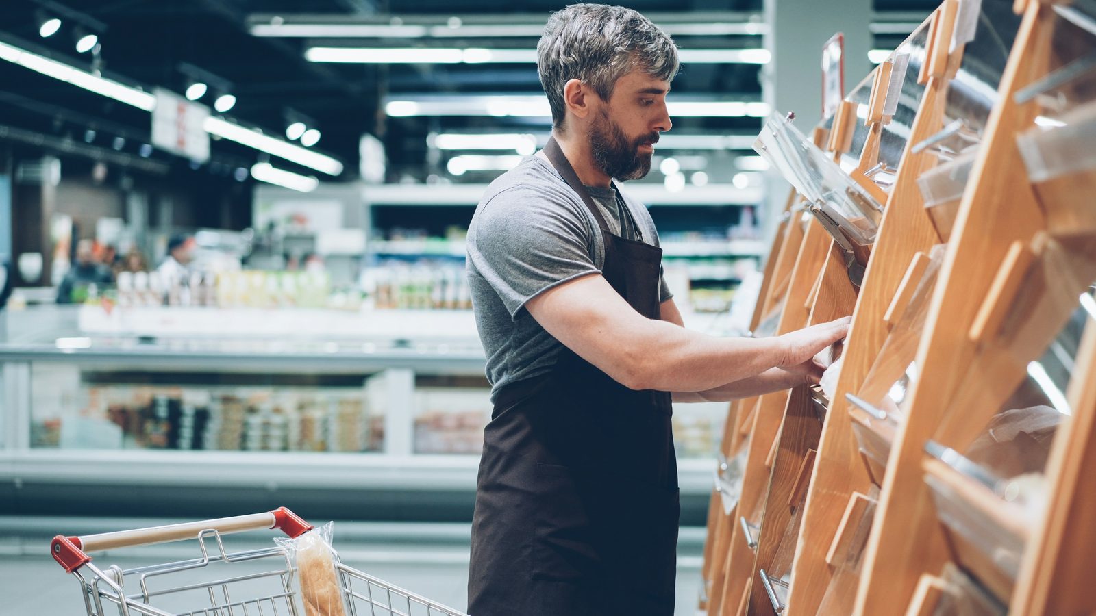 A shop owner in an apron sorting stock on the shelves