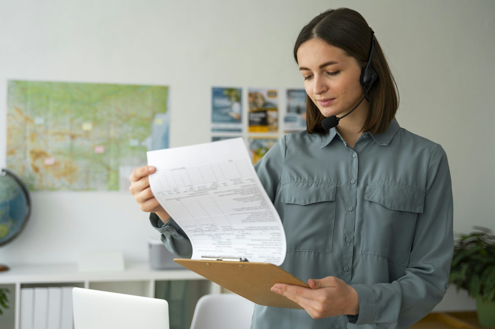 A woman in an office reviewing paperwork on a clipboard