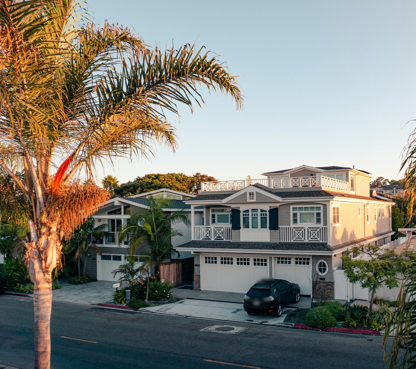 A two-storey house with palm trees in warm evening light