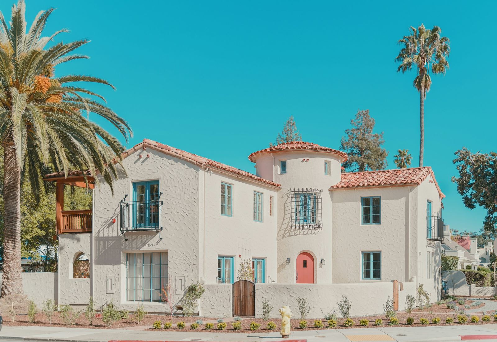 A white Spanish-style house with palm trees