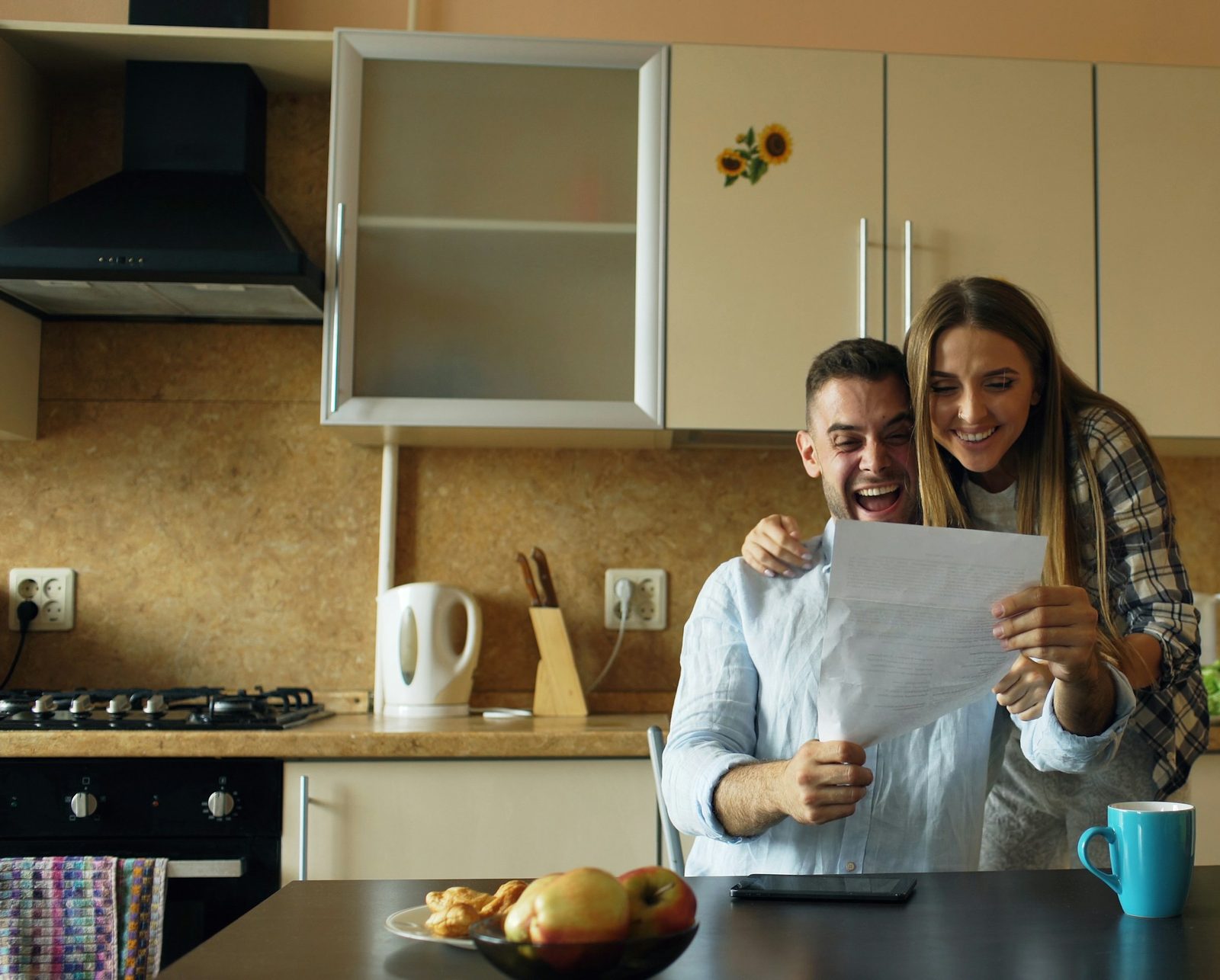 A couple reading a letter together at their kitchen table