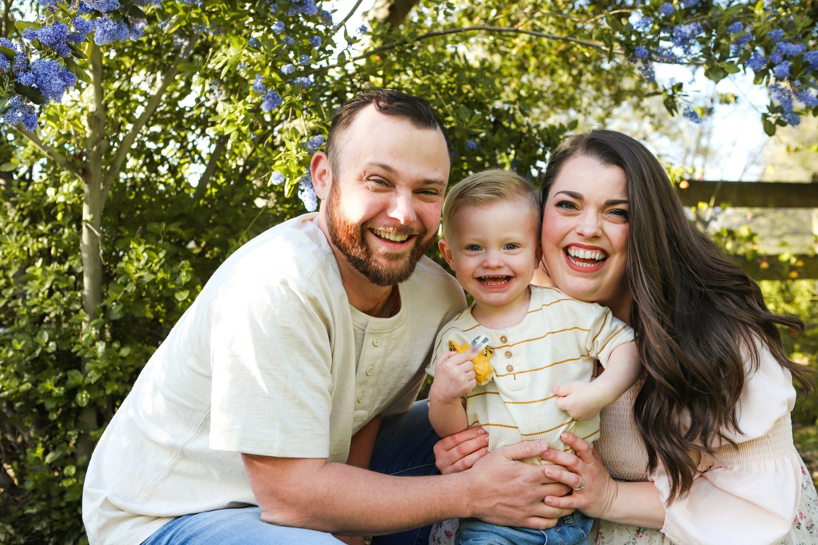 A young couple hugging their toddler outdoors