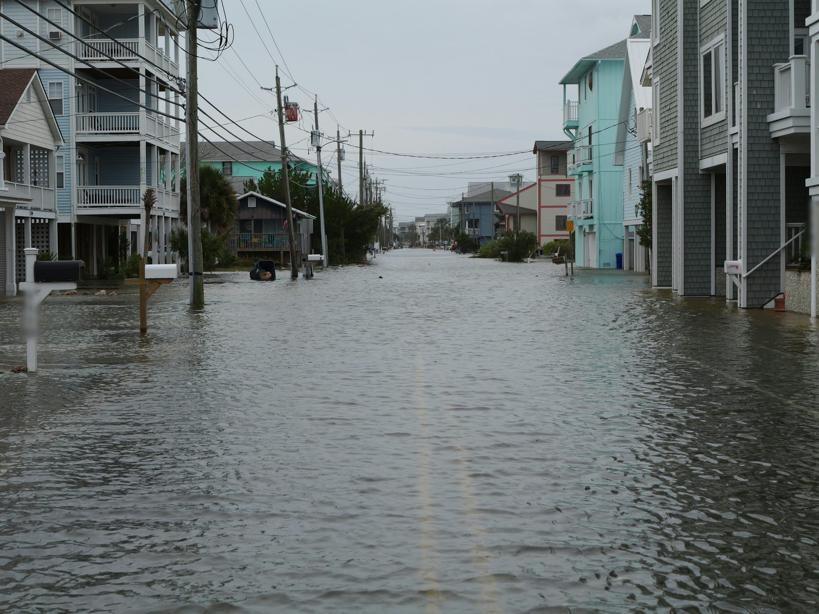 A residential street under floodwater between raised houses