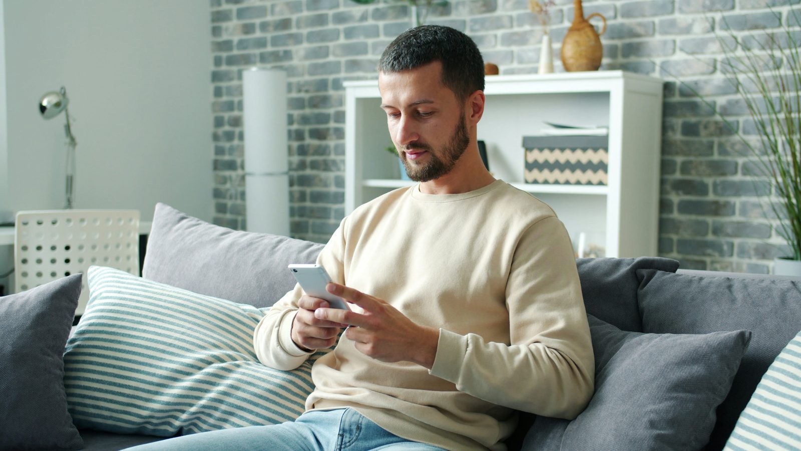 A man on his sofa at home, using his phone