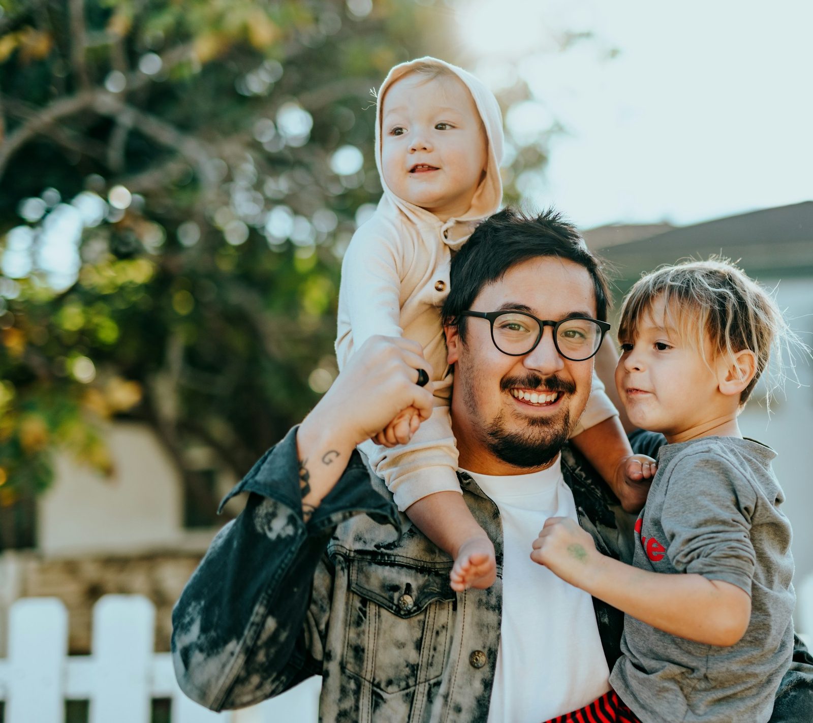 A father carrying his two young children outdoors
