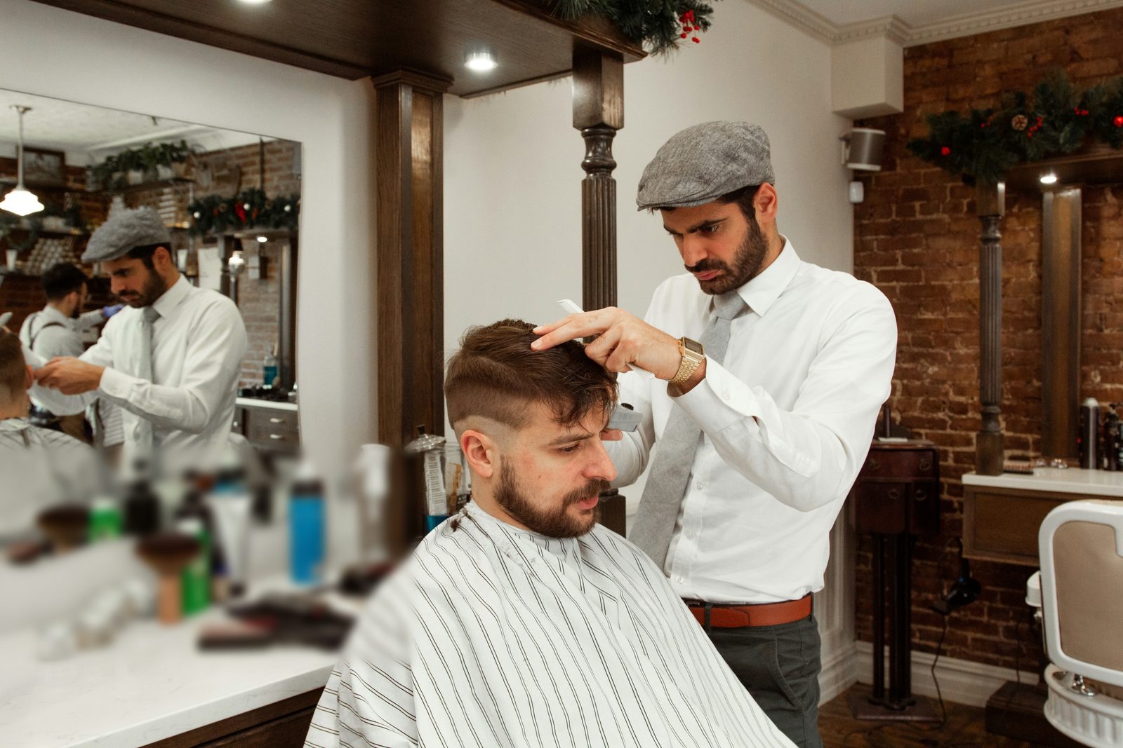 A barber cutting a customer’s hair in his shop