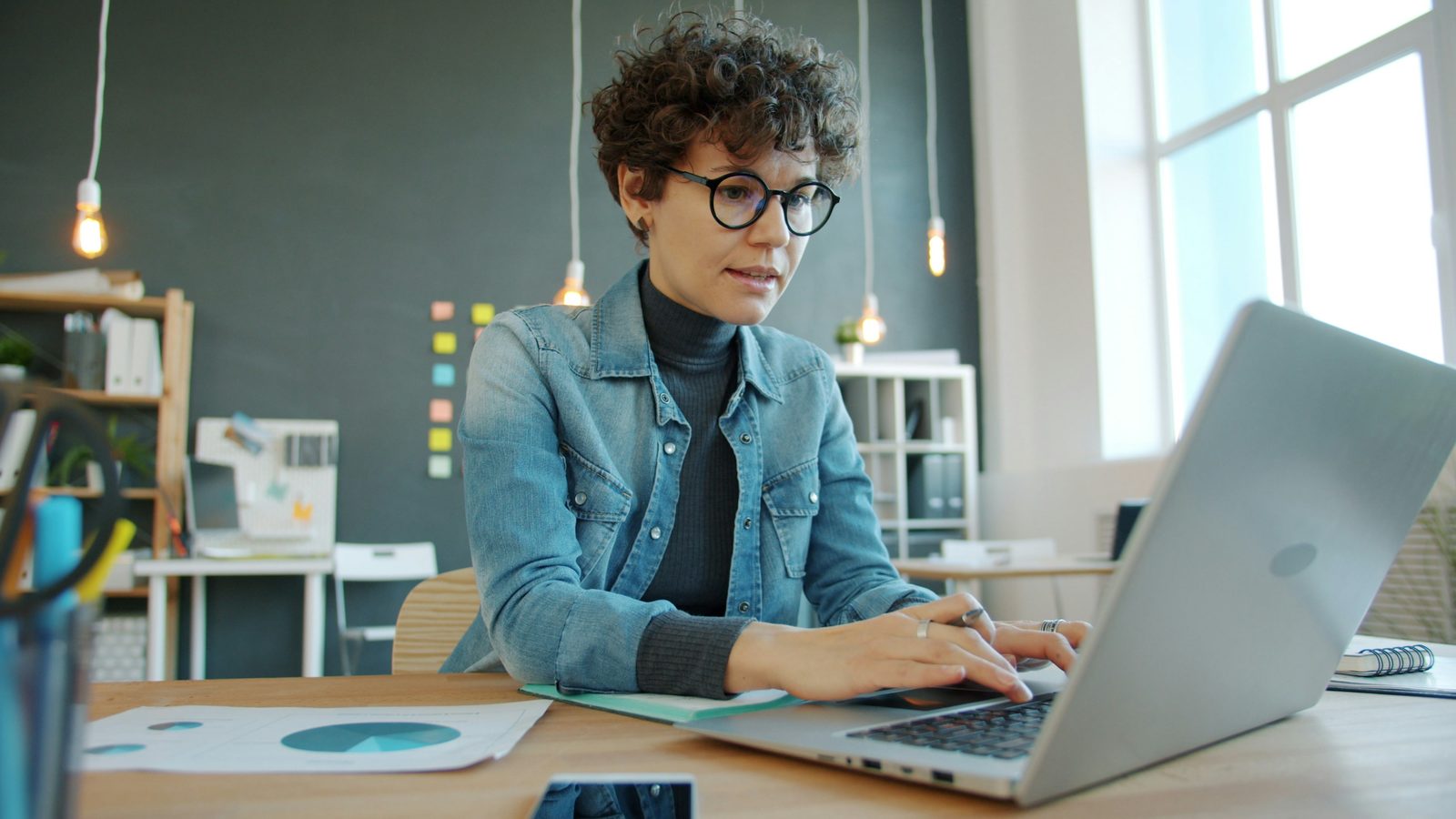 A woman working on a laptop in an office