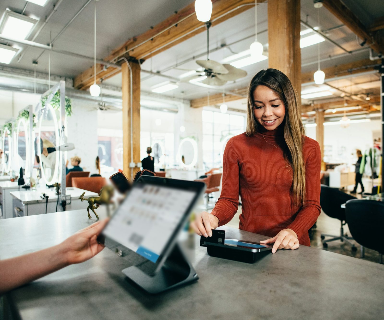 A customer paying by card at a salon checkout counter